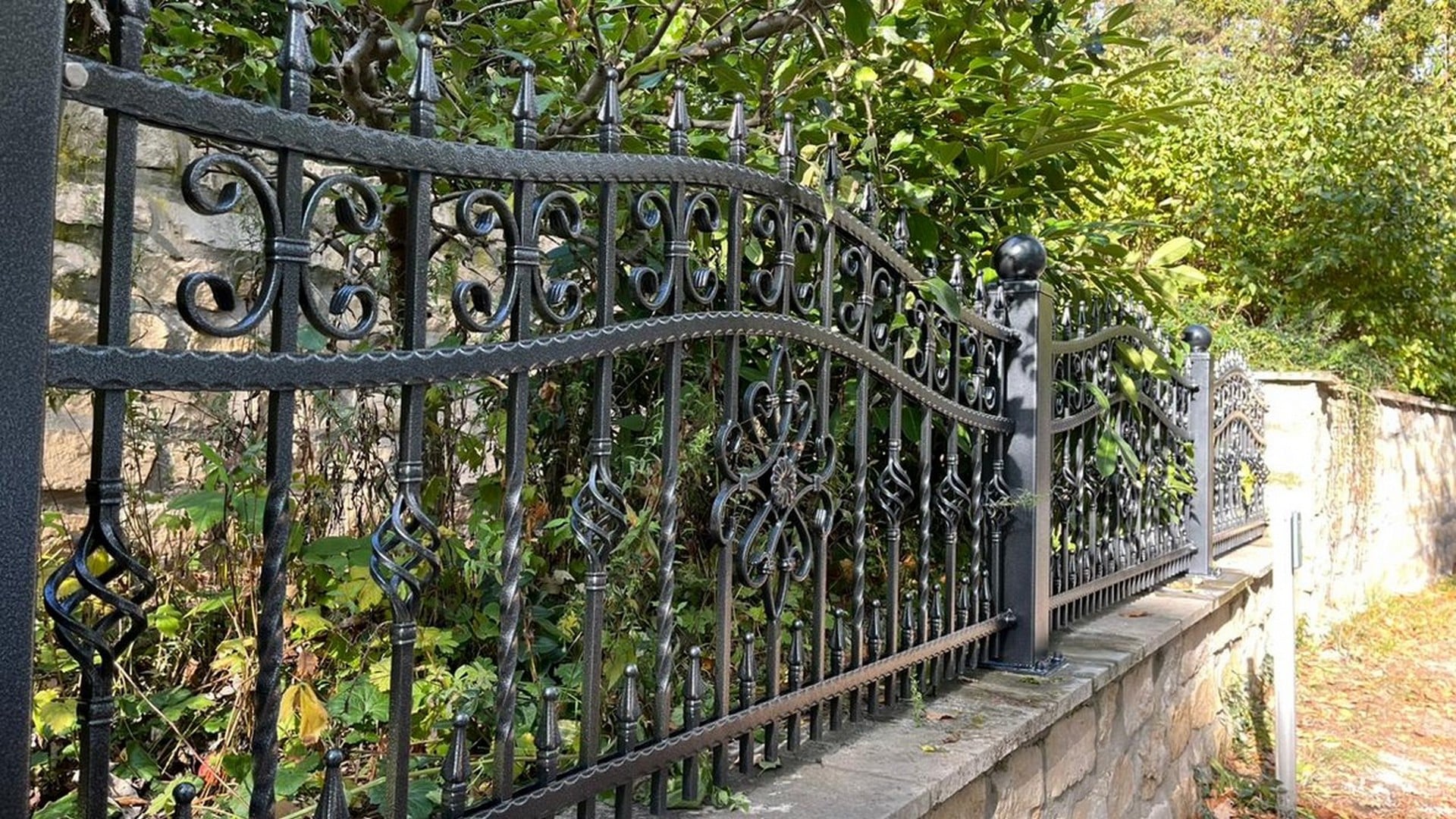 Verziertes schmiedeeisernes Tor und Zaun mit Laubwerk