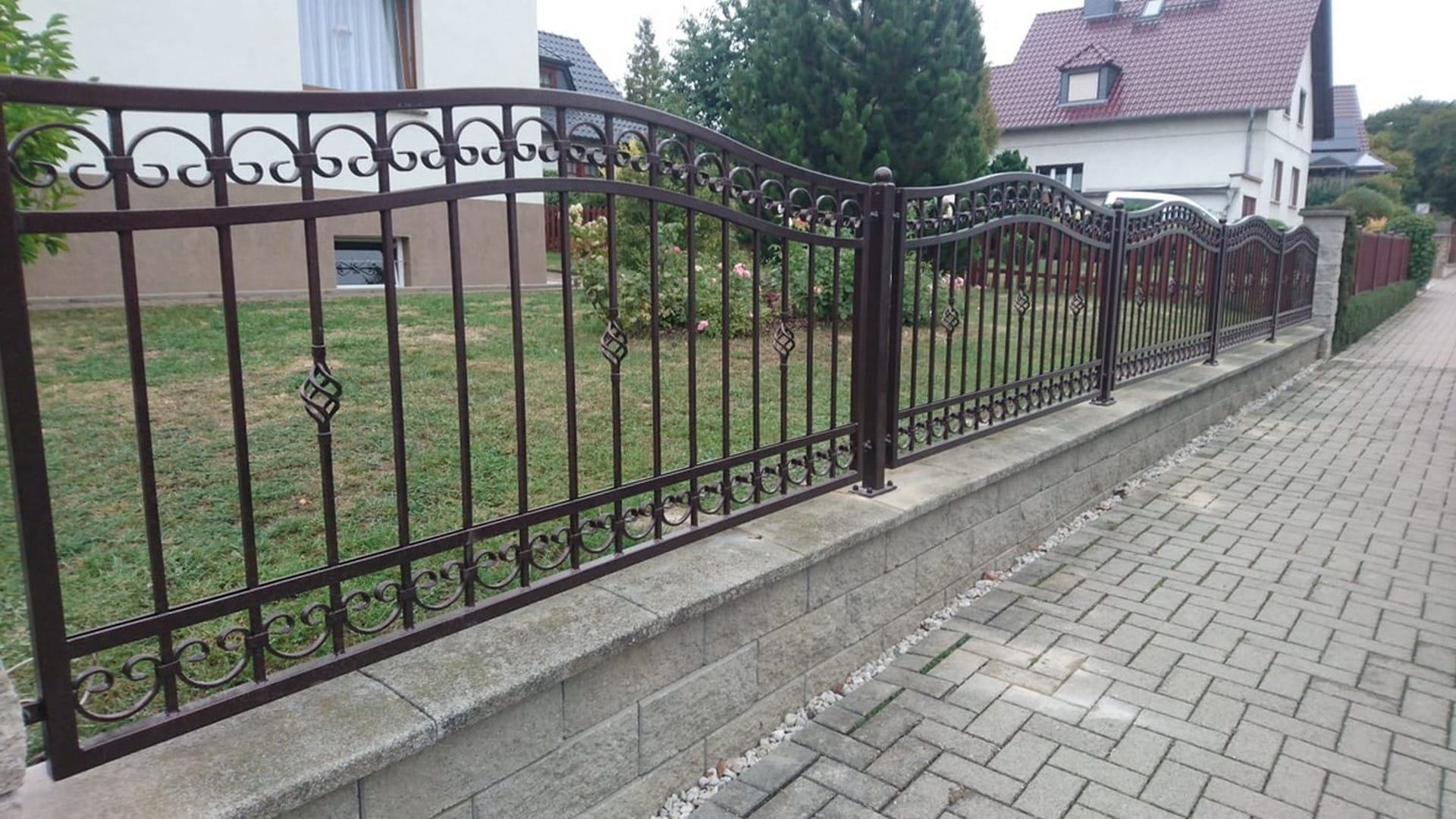 Eiserner Zaun vor einem Wohnhaus.